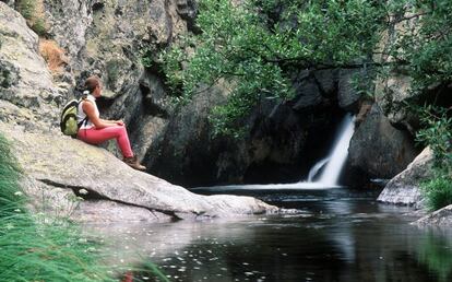 Una excursionista sentada en una roca ante la Poza Negra.