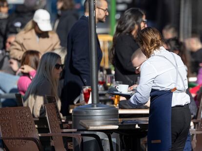 Una camarera recoge una mesa de la terraza de un bar del centro de Sevilla, este viernes.