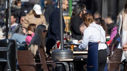 Una camarera recoge una mesa de la terraza de un bar del centro de Sevilla, este viernes.