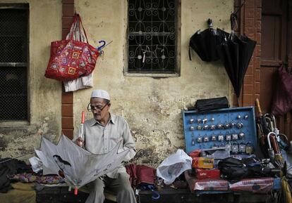 Un trabajador repara un paraguas en su puesto del casco antiguo de Delhi, India.