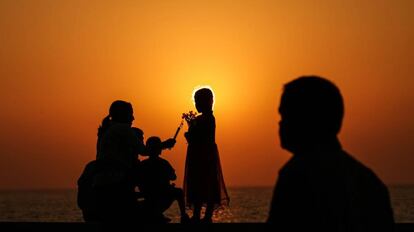 Una familia juega al atardecer en una playa.