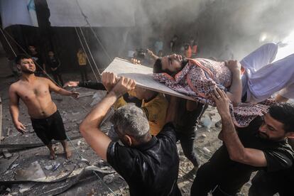 Varios palestinos trasladan a un superviviente de un edificio destruido por un ataque israelí en Jan Yunis, al sur de la Franja.