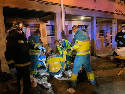 Sanitarios y bomberos atienden a la mujer, tendida en el suelo frente a la vivienda incendiada.