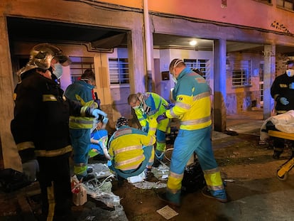 Sanitarios y bomberos atienden a la mujer, tendida en el suelo frente a la vivienda incendiada.