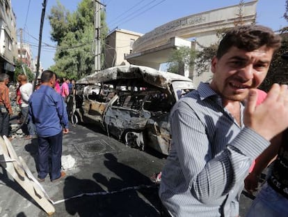 Varias personas observan la camioneta bomba con la que se ha efectuado el atentado en el barrio druso de Jaramana.