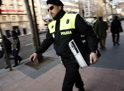 Un policía lleva un ordenador intervenido tras el registro de la Junta Municipal del Distrito de Salamanca.