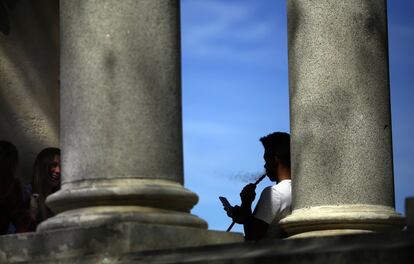 Un joven fuma en cachimba junto a las columnas de la estatua ecuestre del Rey Alfonso XII.