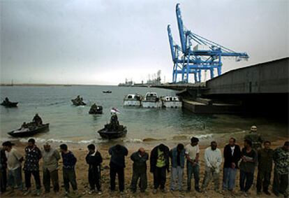 Miembros de la tercera brigada de los <i>marines</i> reales británicos vigilan a un grupo de prisioneros iraquíes en el puerto de Um Qasr, al sur del país.