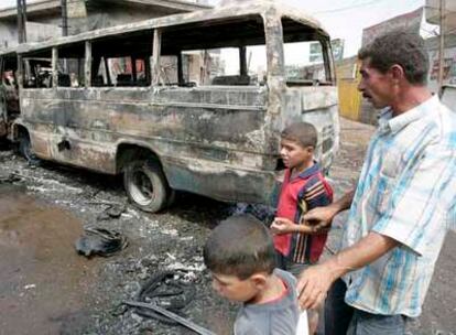Un hombre y dos niños contemplan los restos de vehículos en el lugar de la explosión de un coche bomba en la plaza al-Tayran en Bagdad.