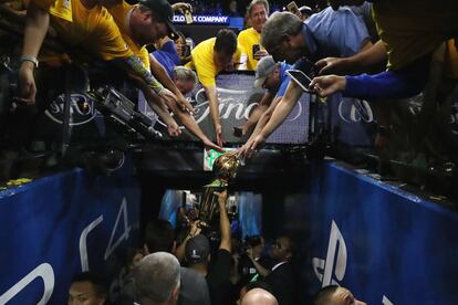 Stephen Curry lleva el trofeo a los vestuarios mientras los aficionados intentan alcanzarlo.