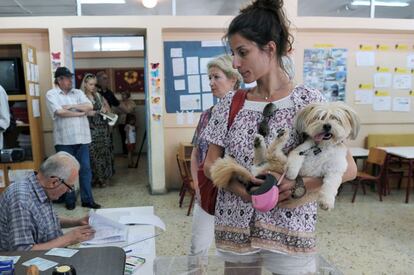Una mujer espera junto con su perro antes de votar en un colegio electorl en Atenas.
