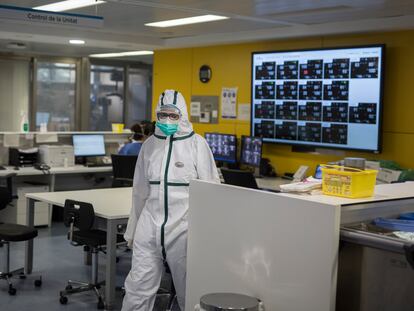 Un trabajador sanitario, con traje protector frente al coronavirus, en la UCI del hospital Vall d’Hebron de Barcelona.