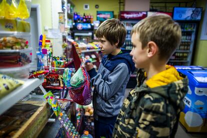 Misha (centro) acude a la tienda que hay debajo de su casa a comprar patatas junto a su vecino Nikita. Esta es una de las tiendas de las que se surtieron de alimentos con permiso de sus propietarios durante la ocupación rusa. 