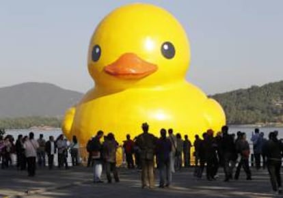 Turistas observan un pato gigante amarillo instalado el pasado 26 de septiembre de 2013 en el lago cerca del Palacio de Verano en Pekín (China). La instalación de 18 metros, creada por el artista holandés Florentijn Hofman. EFE/Archivo