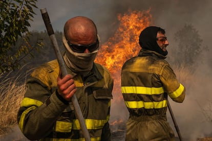 Dos voluntarios realizan labores de extinción en el incendio de Oímbra (Ourense) el martes 19 de agosto.