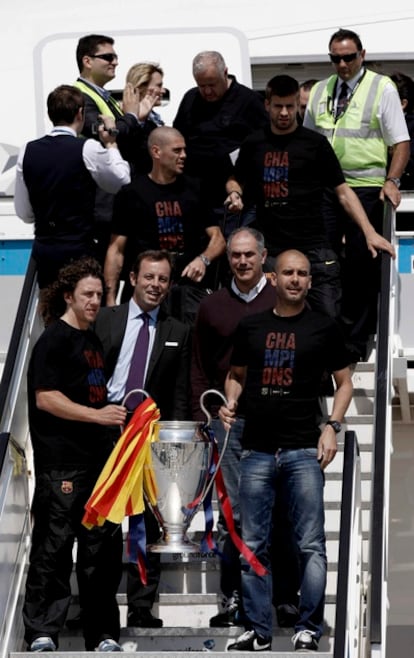 Puyol y Guardiola sujetan la Copa tras aterrizar en Barcelona.