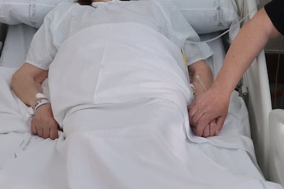 Juan José Márquez sujetando la mano de su madre, Encarnación Plaza, en el Hospital Fundación Jiménez Díaz, en Madrid.