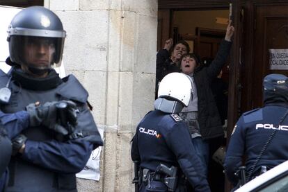 Los agentes sacan del edificio, esposadas, a dos de las mujeres detenidas.