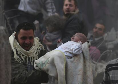 Un hombre lleva un bebé que sobrevivió a lo que los activistas dicen que fue un ataque aéreo de las fuerzas leales al presidente sirio, Bashar al-Assad en el barrio de Duma.