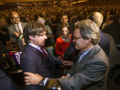 Carles Puigdemont y Artur Mas se saludan, en presencia de Carme Forcadell, durante el acto central del Pacto Nacional por el Referéndum.