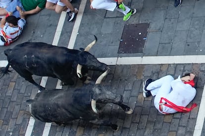 Un corredor se protege al paso de varios toros de la ganadería Cebada Gago en el tramo de la Estafeta de Pamplona.