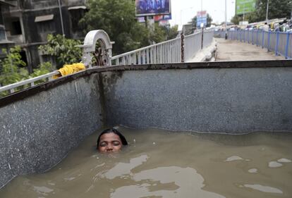 Una adolescente se refresca en un tanque de agua utilizado para la construcción de carreteras durante una tarde calurosa en Bombay (India).