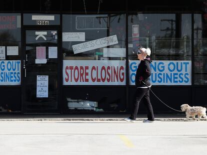 Mulher passa diante de vitrine de uma loja fechada, na quarta-feira, em Niles (Illinois).