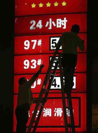 Unos operarios cambian el precio del carburante en una estación de servicio de Chengdu.