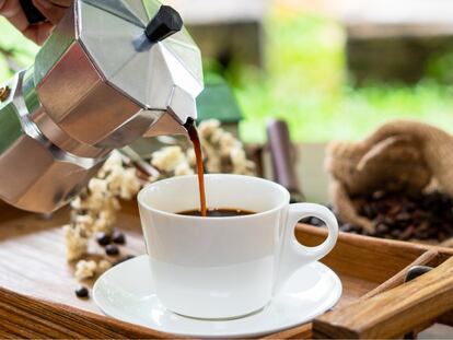 Una persona sirve una taza de 'espresso' elaborado en una cafetera italiana.