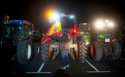 Un agricultor coloca una bandera de España en uno de los 250 tractores estacionados en un descampado de Torrejón de la Calzada (Madrid). 