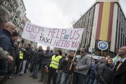 Los taxistas muestran una pancarta en la que piden ayuda a Europa, ante la sede del PP.