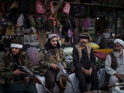Guerrilleros talibanes descansan junto a dos vendedores de un mercado local de Kabul, este viernes.