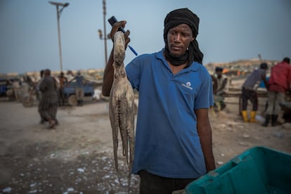 Un pescador muestra su captura. Los hombres venden sus capturas individualmente a pequeños intermediarios en el puerto.