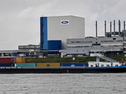 FILE - A container ship passes the Ford car plant in Cologne, Germany, May 4, 2020. Ford said that it will cut 3,800 jobs in Europe over the next three years in an effort to streamline its operations as it contends with economic headwinds and increasing competition on electric cars. The automaker said that 2,300 jobs will go in Germany. (AP Photo/Martin Meissner, File)