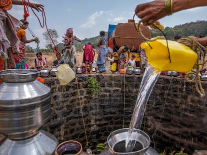 A villager pours water into a canister as others gather around a well to draw water in Telamwadi, northeast of Mumbai, India, May 6, 2023. T