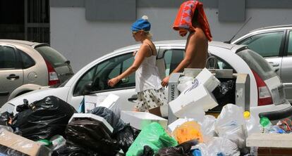 Dos vecinos de Rota pasan cerca de un contenedor de basura.