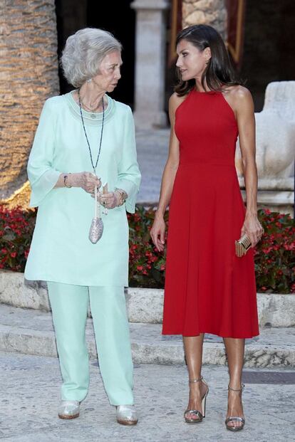 La reina Letizia parece decidida a acallar a quien ponga en duda su relación con doña Sofía y, por ello, este verano las salidas de ambas se han sucedido sin parar. En la imagen, en la recepción en la Almudaina el miércoles por la noche. La Reina apostó todo al rojo con un vestido sin mangas, cuerpo entallado y falda evasé con ligero vuelo. Por su parte, la reina émerita optó por un conjunto de camisola y pantalón recto ancho con acabado liso en color pastel, concretamente, en verde menta.