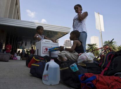 Una familia con algunas pertenencias hace fila a la espera de ser evacuada de la ciudad