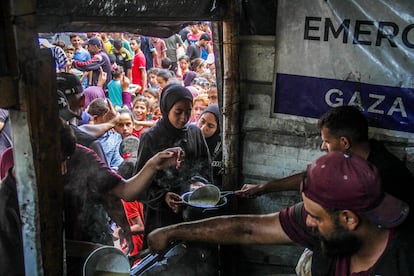 Palestinos viviendo en el campo de refugiados de Jabalia forman una larga cola para recibir alimentos distribuidos por una ONG.