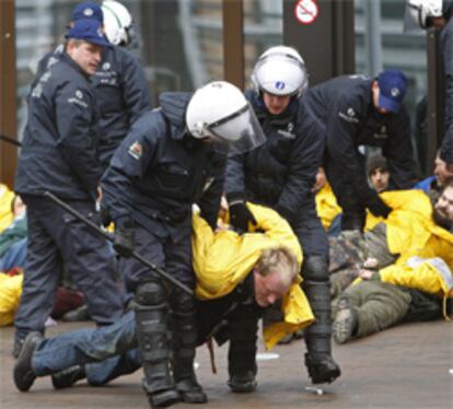 Agentes de la Policía retiran a los activistas de Greenpeace de la puerta principal de la sede de la UE en Bruselas durante la reunión de ministros de Economía de la UE.