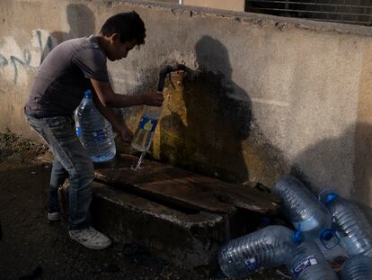 Un niño rellena una garrafa de agua y varias botellas en una fuente pública en el municipio de Byblos, al norte de Beirut.