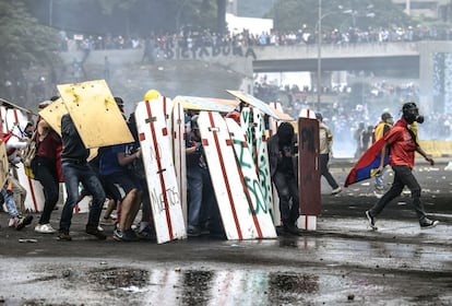 Un grupo de activistas opositores se refugia bajo sus escudos durante los enfrentamientos con la policía, en Caracas, el 24 de junio de 2017.