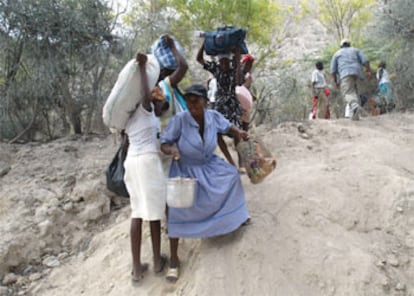 Varias mujeres haitianas abandonan sus hogares con sus pertenencias a cuestas.