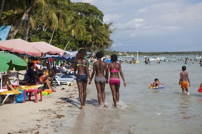 Três jovens passeiam pela praia de Boca Chica.