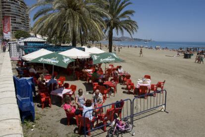 Vecinos y turistas de Málaga, ayer, en un chiringuito situado sobre la arena de la playa.