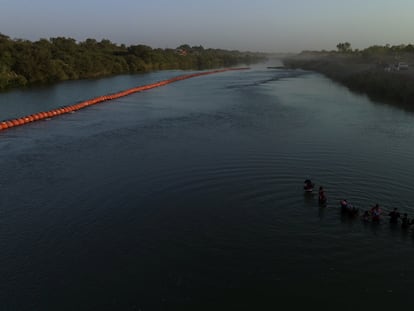 Migrantes pasan una serie de boyas en la orilla del río Grande para entrar a los Estados Unidos desde México.