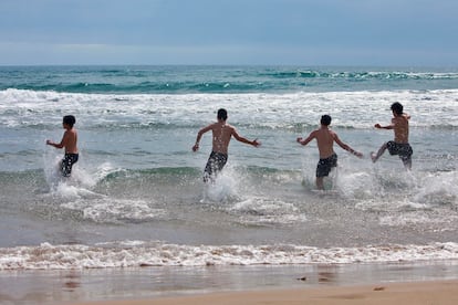 Varios jóvenes disfrutan del mar, este lunes, en la playa de Gandía. La Comunidad Valenciana estrena íntegramente su pase a la fase 2 de la desescalada, que entre otras medidas de relajamiento contempla el uso y disfrute, con nuevas condiciones de seguridad y control, de las playas del litoral, además de la apertura de centros comerciales, de bares y restaurantes al 40 % del aforo.