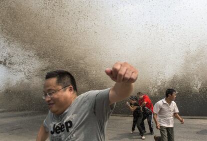 Unos visitantes huyen de una gran ola causada por una marejada que subió por encima del rompeolas en el río Qiantang, antes de desembocar en el mar de China Oriental, en la provincia china de Zhejiang.