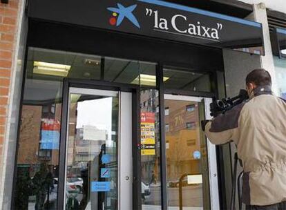 Un reportero gráfico toma imágenes de la sucursal bancaria de la calle Aquitania atracada esta mañana.