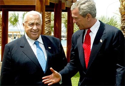 Sharon sonríe a Bush mientras éste le tiende la mano.